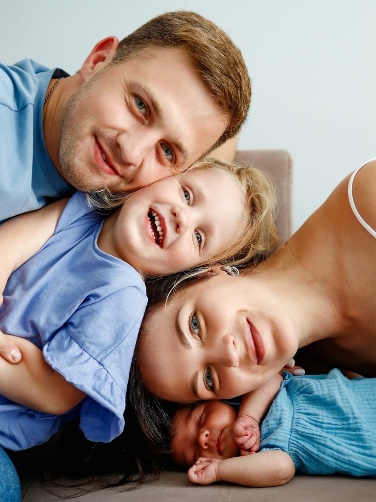 a-man-and-two-children-laying-on-a-couch-v92xhn7kseu